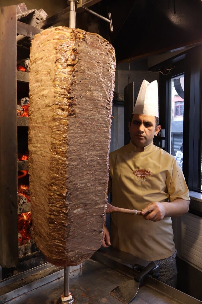Döner ustası, odun ateşi ocağının yanında yaprak döner konisiyle