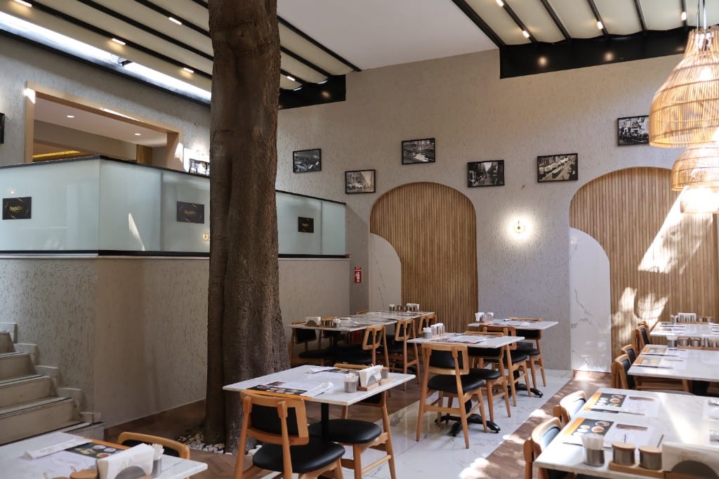Salonun ortasındaki ağaç, asma kat cam korkuluk ve kemerli ahşap nişler