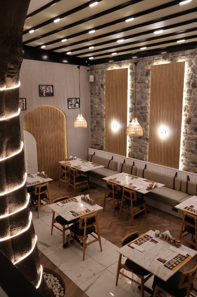 Taş duvar, ahşap çıtalar, hasır avizeler ve banket sıralı salon